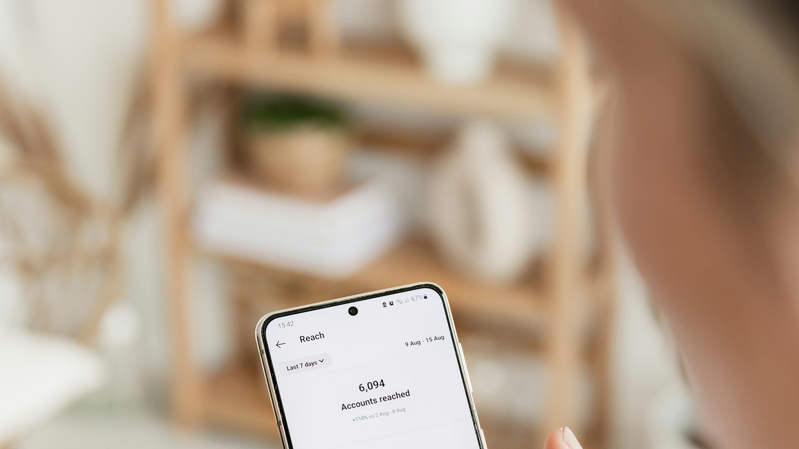 A hand holding a phone showing an app dashboard