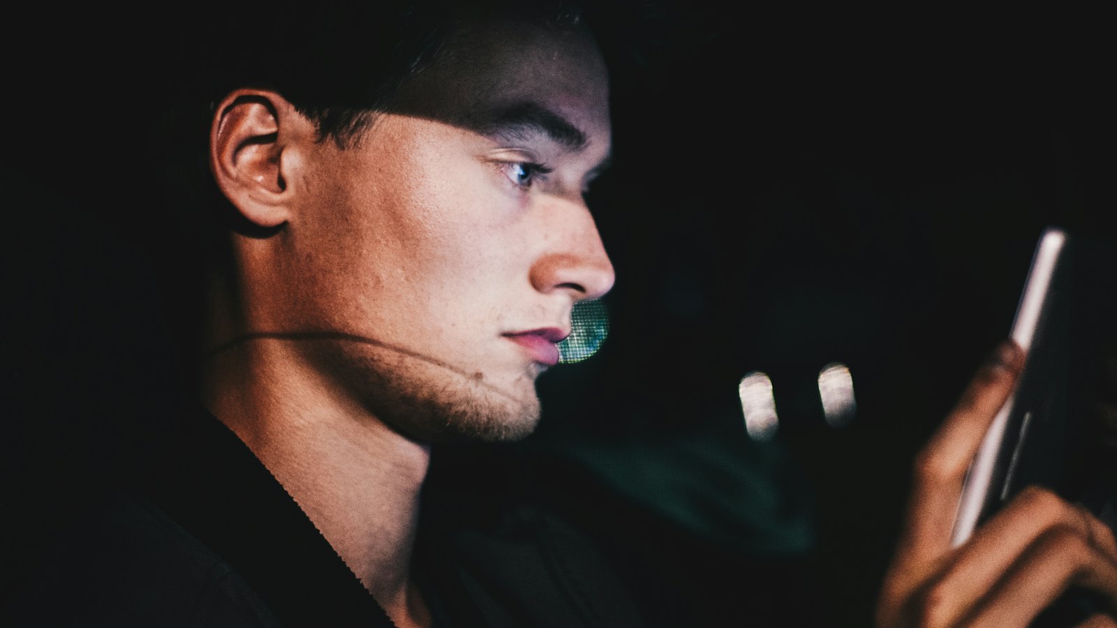 A man listening to his phone in the dark