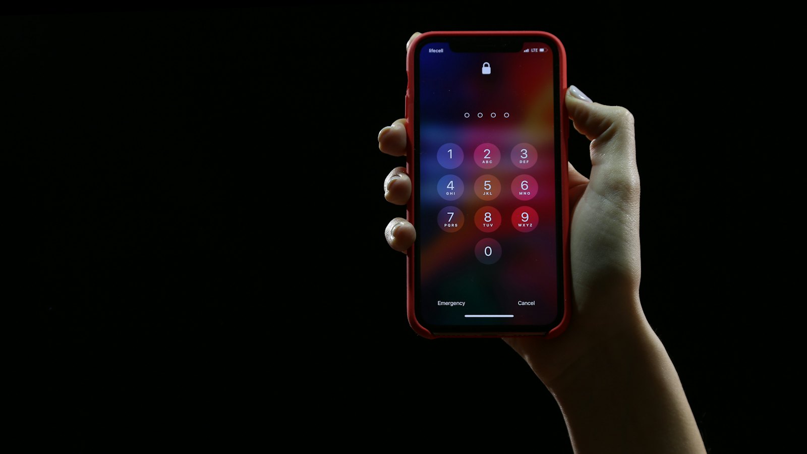A hand holding up a phone showing a keypad against a dark background