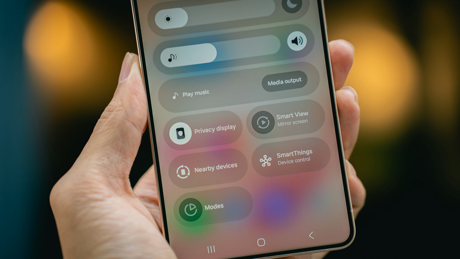 A hand holding a phone showing a settings menu