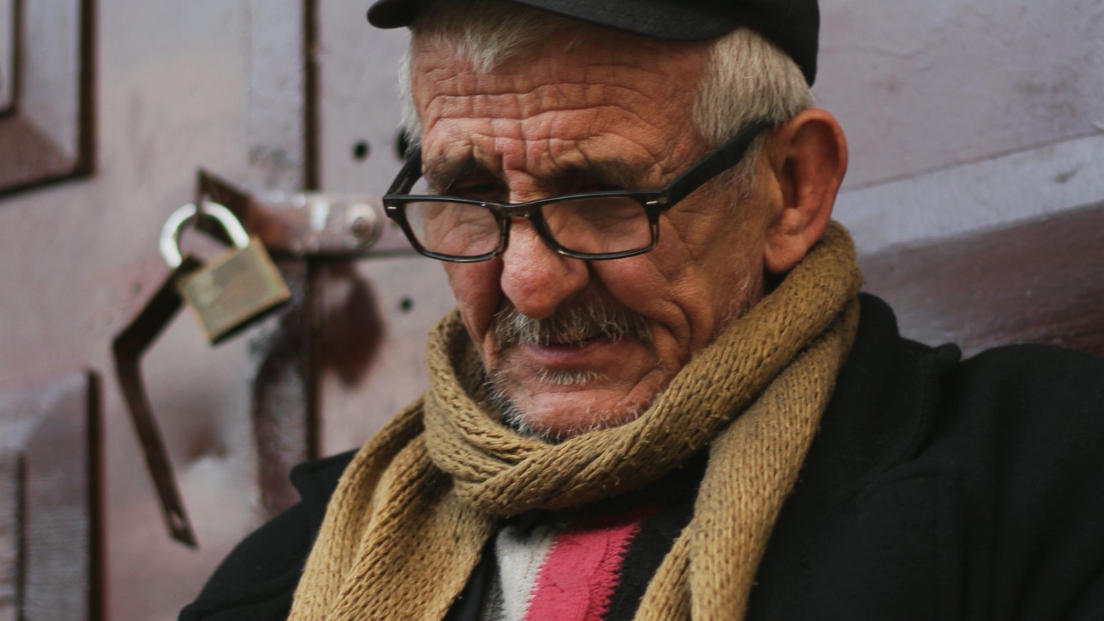 An older man in a scarf looking concerned