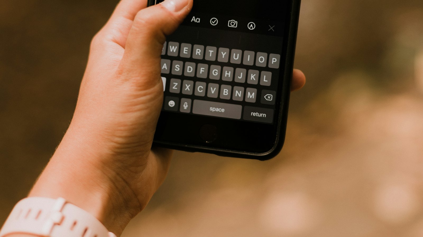 A hand holding a phone with the keyboard open