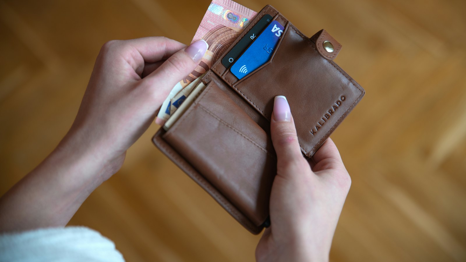 Hands opening a leather wallet with cards