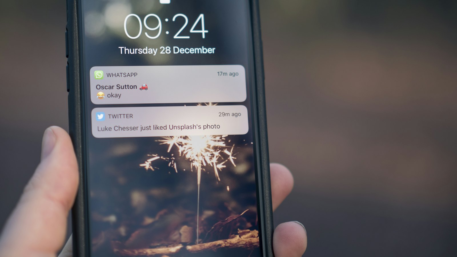 A hand holding a phone with notifications on the lock screen
