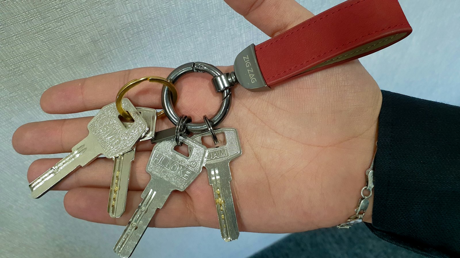 A hand holding a set of keys on a leather strap