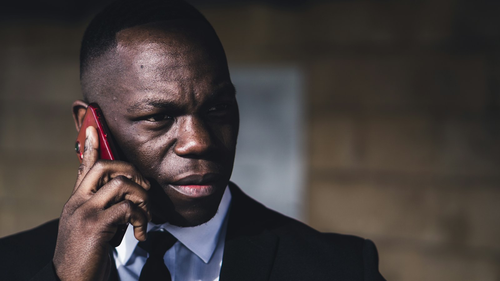 A serious-looking man in a suit on a phone call
