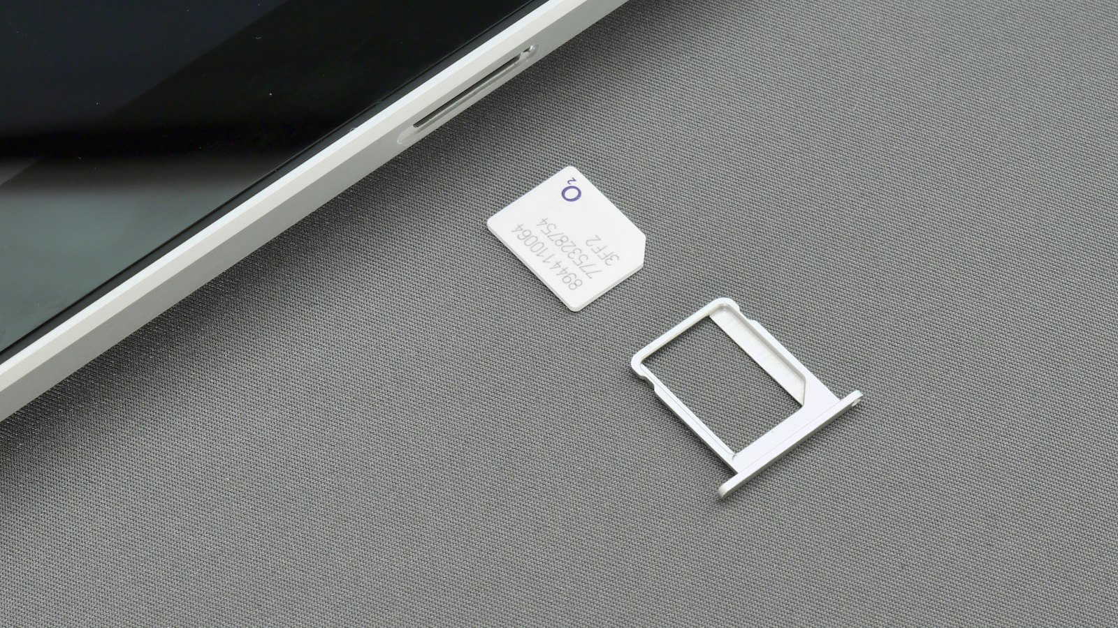 A SIM card and tray beside a phone, ready to move to a new device