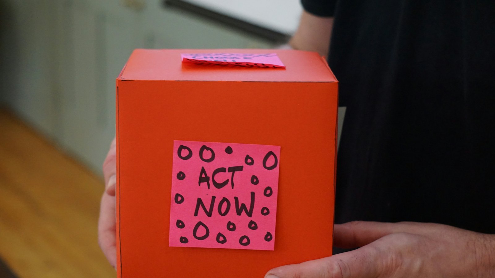 A donation box with an act now note
