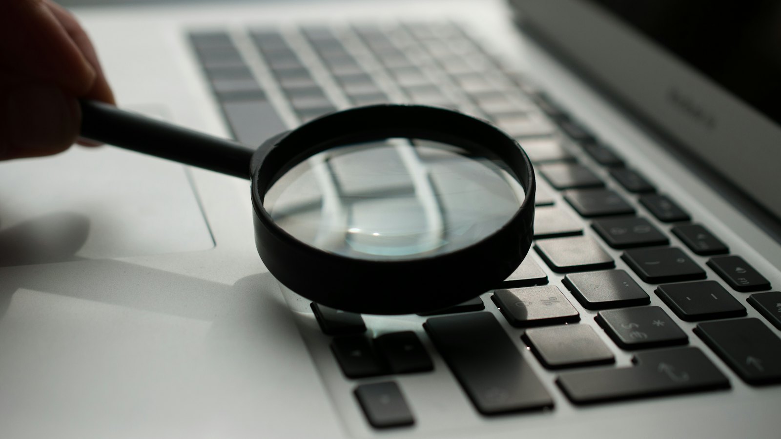 A magnifying glass held over a laptop keyboard