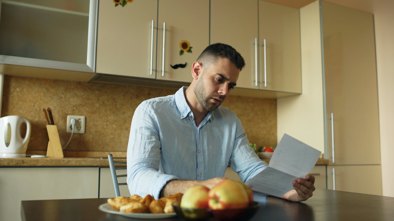 A man reading a letter at a kitchen table