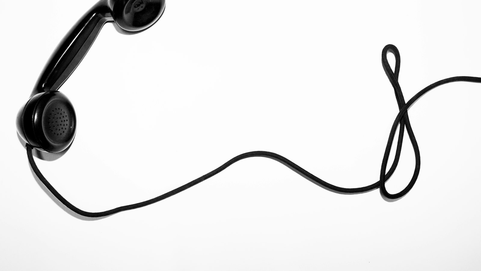 A black telephone handset with a coiled cord on a white background