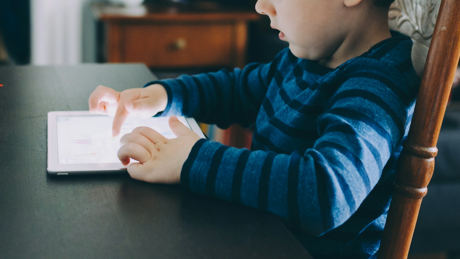 A young boy using a tablet at a table