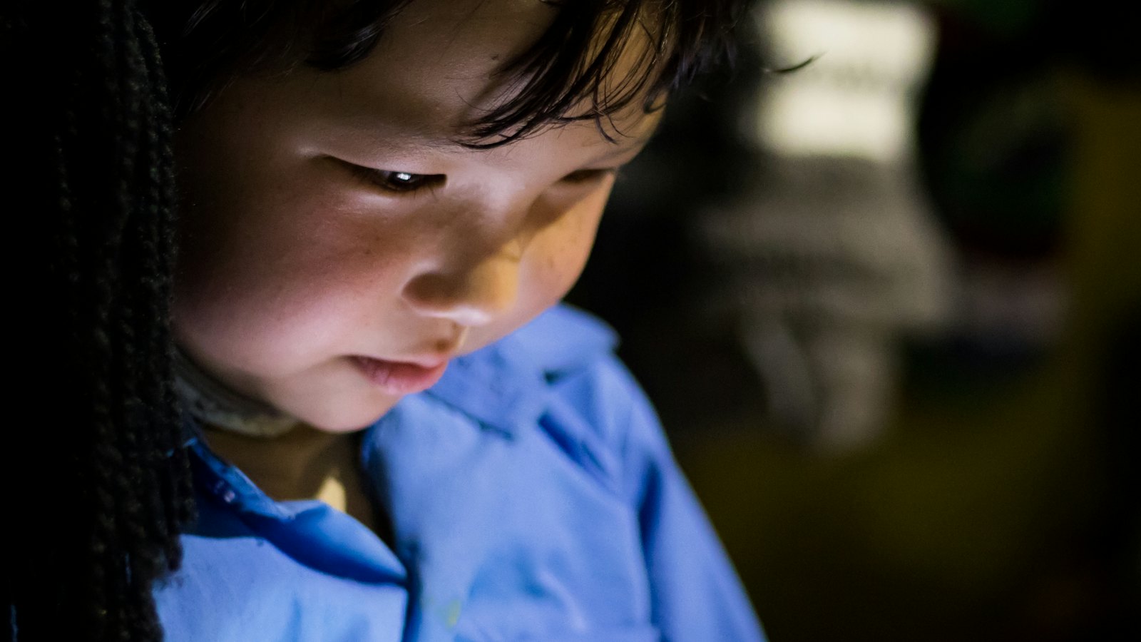 A child looking at a screen in low light