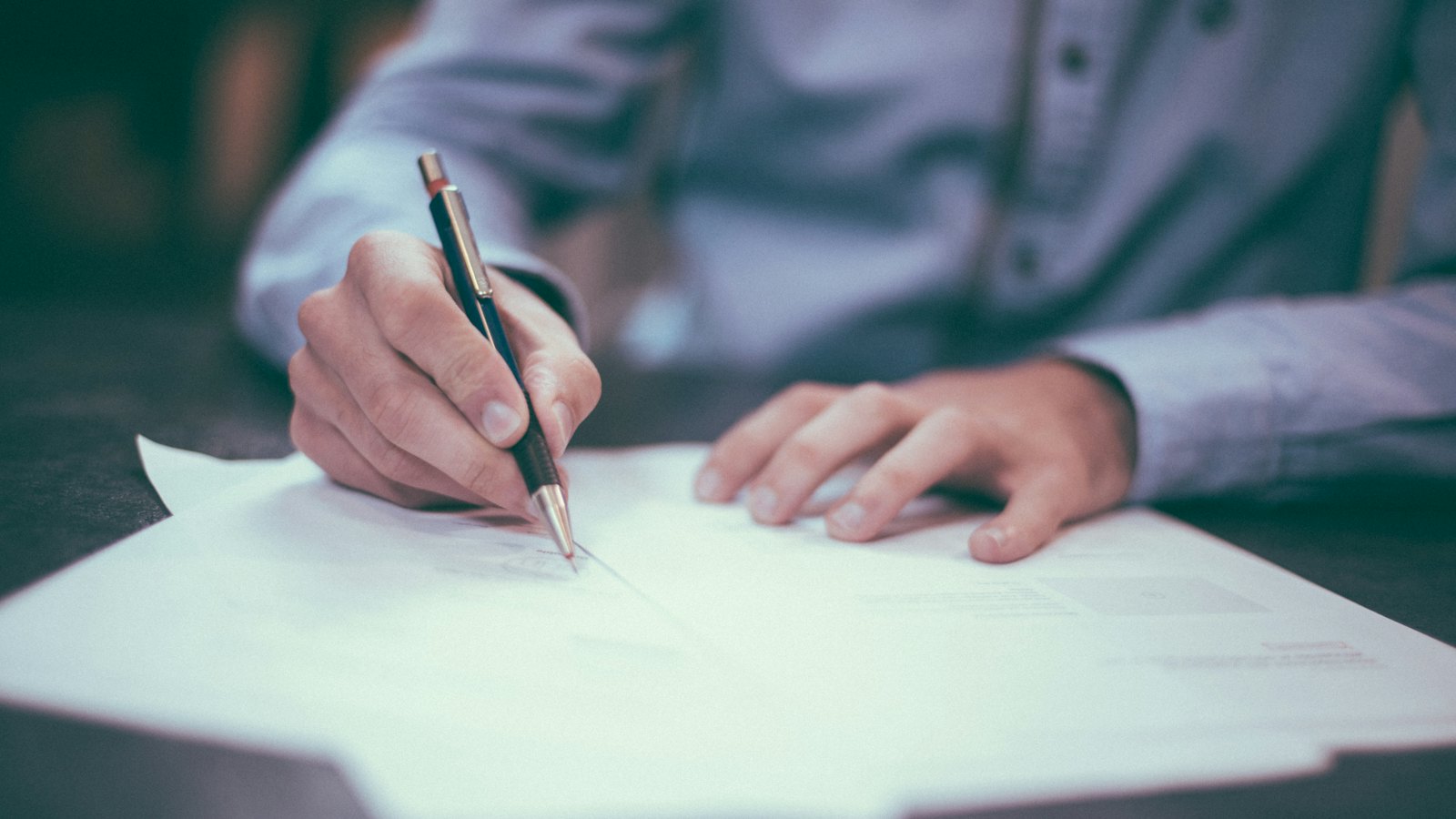 A man writing on a sheet of paper with a pen