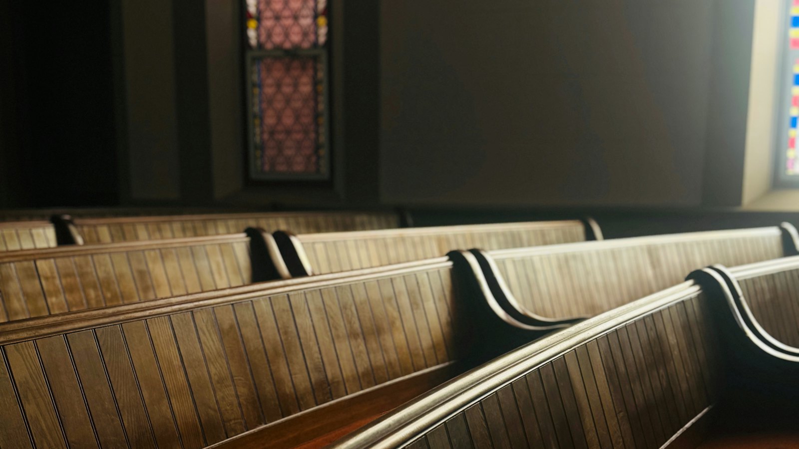 Rows of empty wooden pews in a dim church