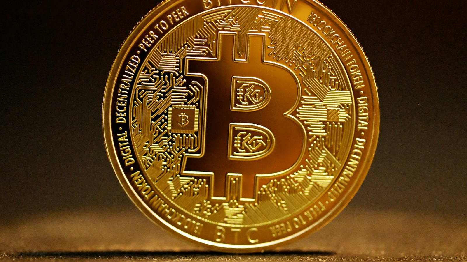 A gold bitcoin coin on a dark surface