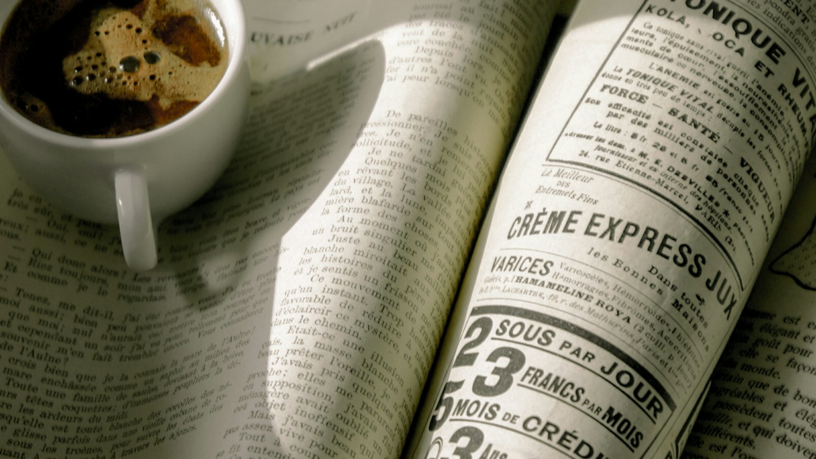A cup of coffee beside an open newspaper