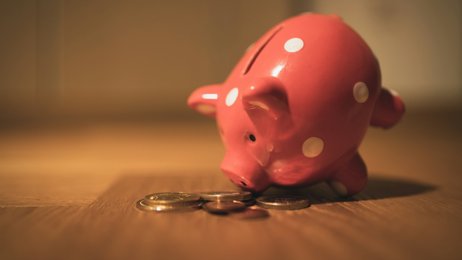 A red piggy bank with coins on a table