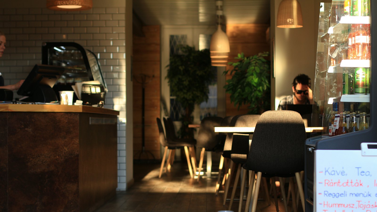 The warm interior of a quiet cafe with tables and plants