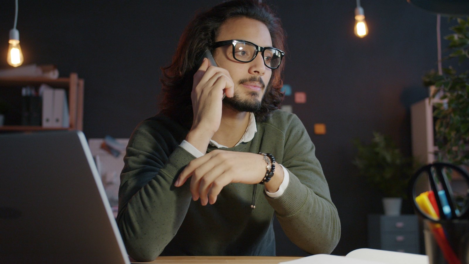 A man at his desk listening intently on a phone call