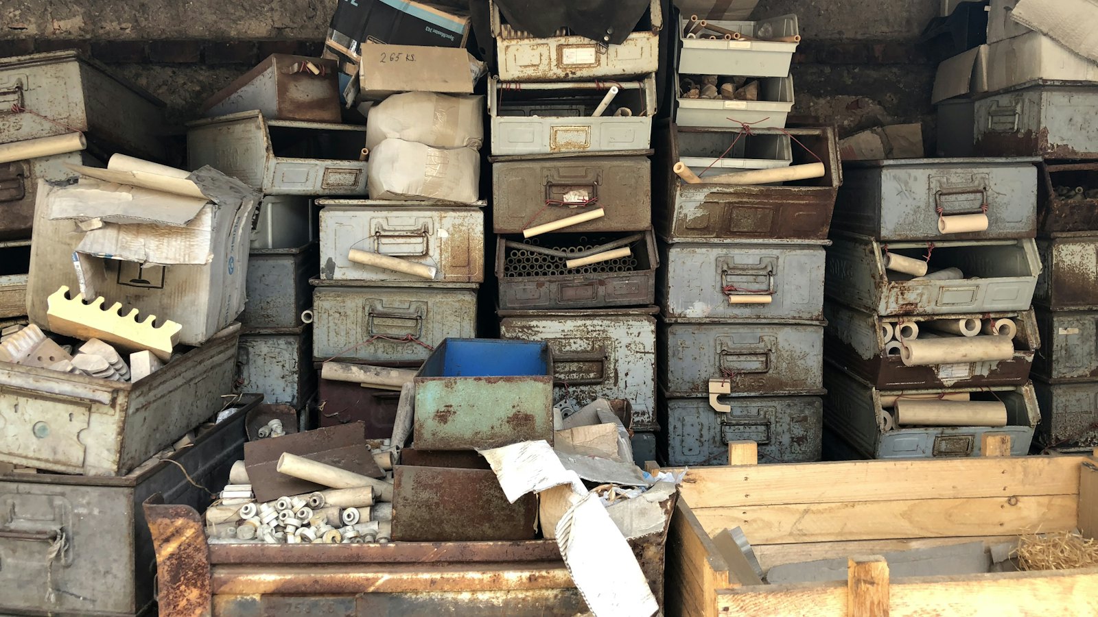 Piles of old metal boxes and drawers stacked in a storeroom