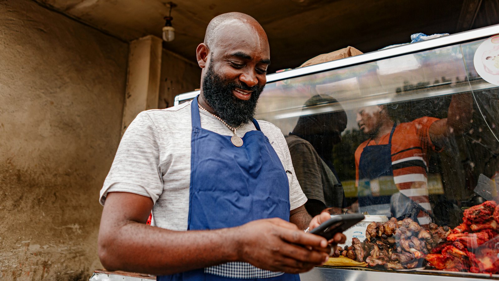 A shop owner in an apron checking his phone