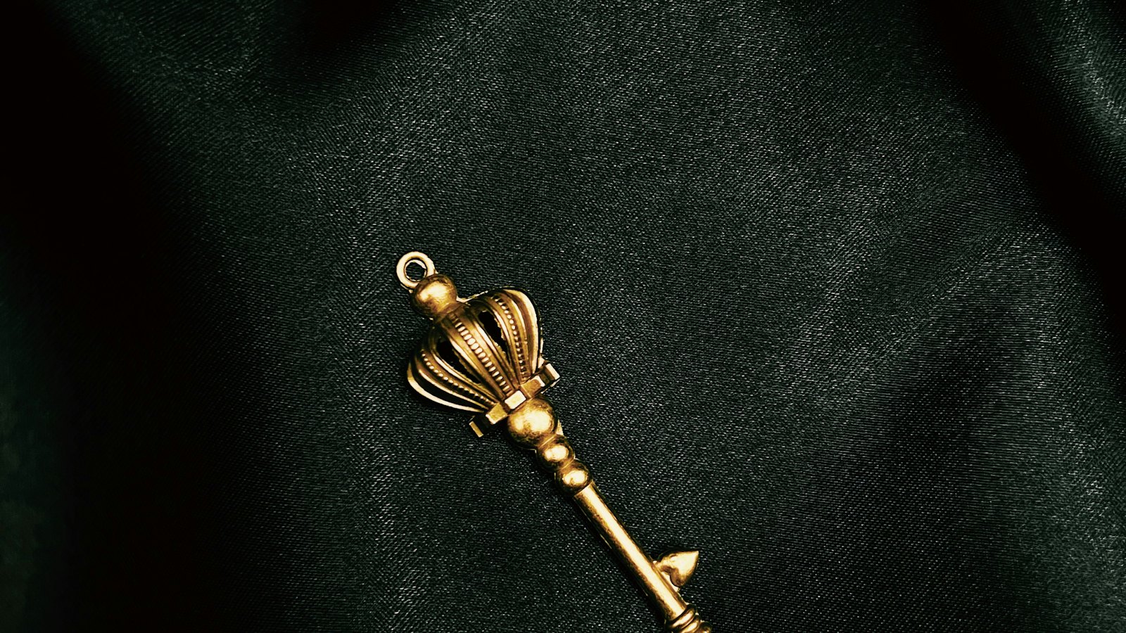 An ornate gold key on a dark green cloth