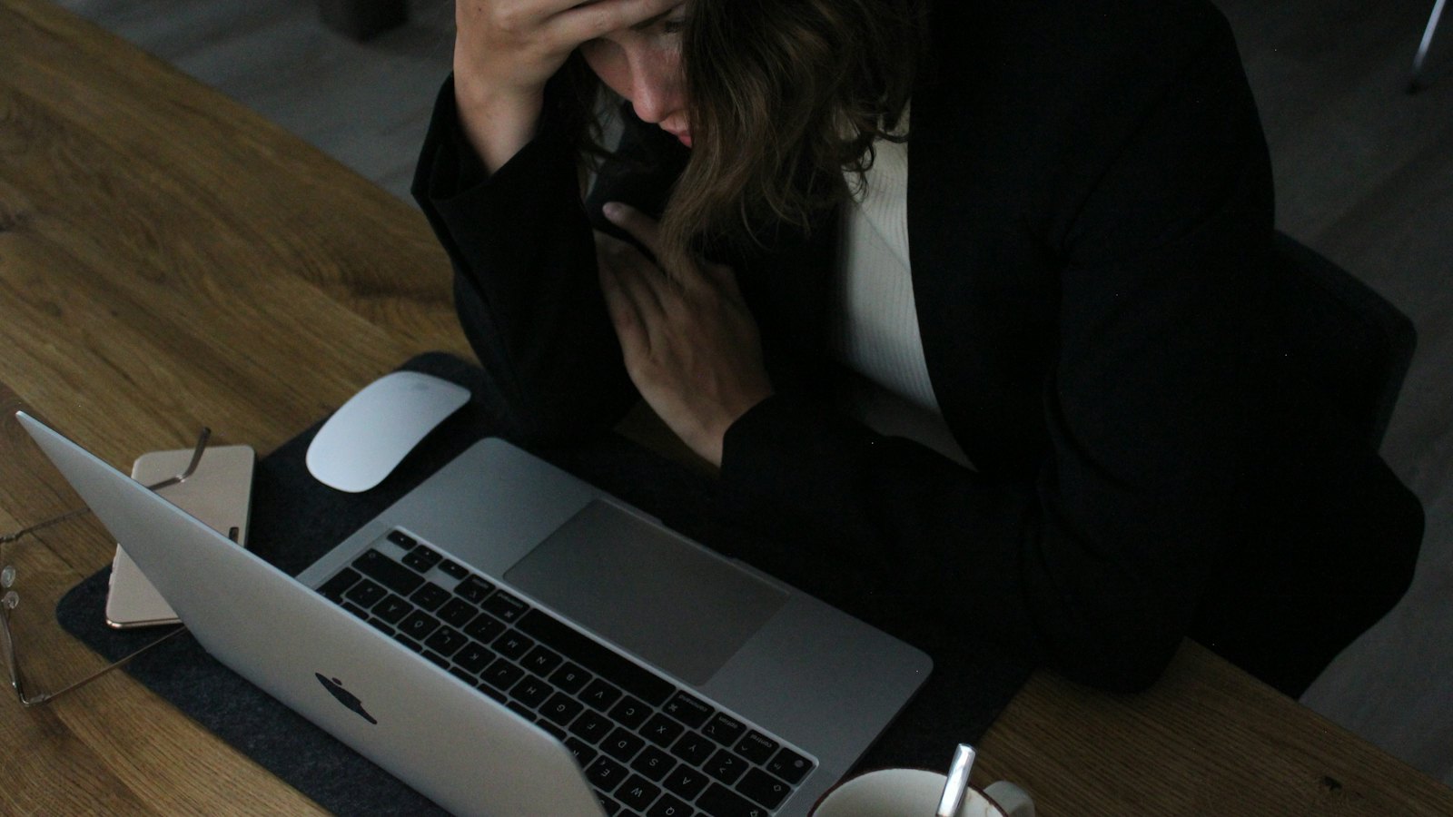 A worried person with their head in their hands at a laptop
