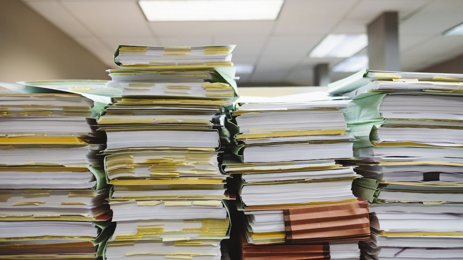 Tall stacks of paper files and folders on a desk