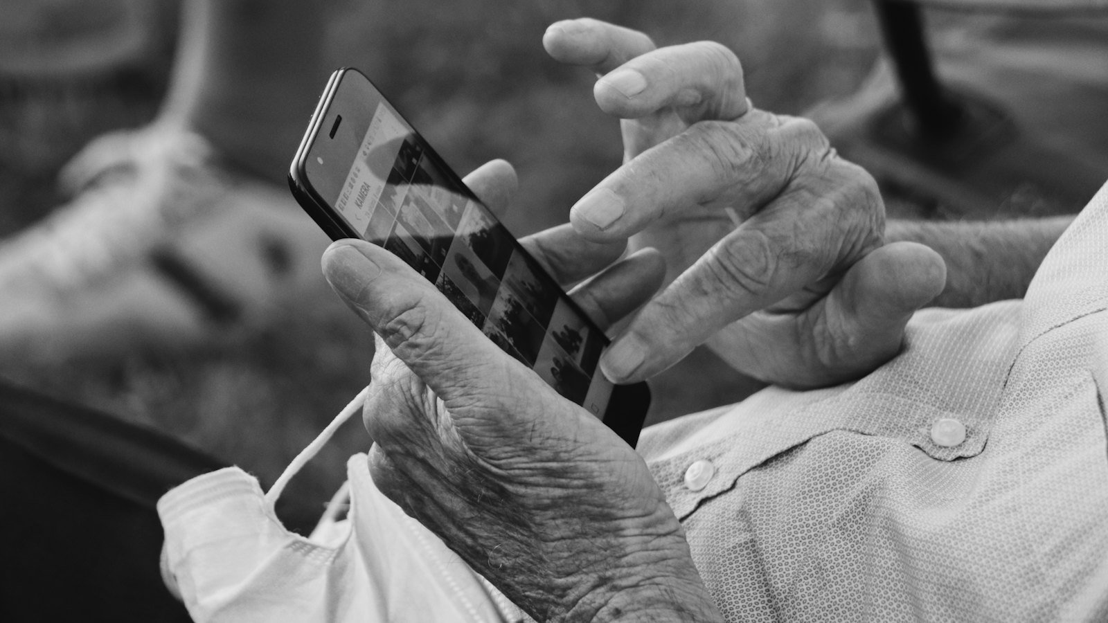 A black and white close-up of hands holding a phone