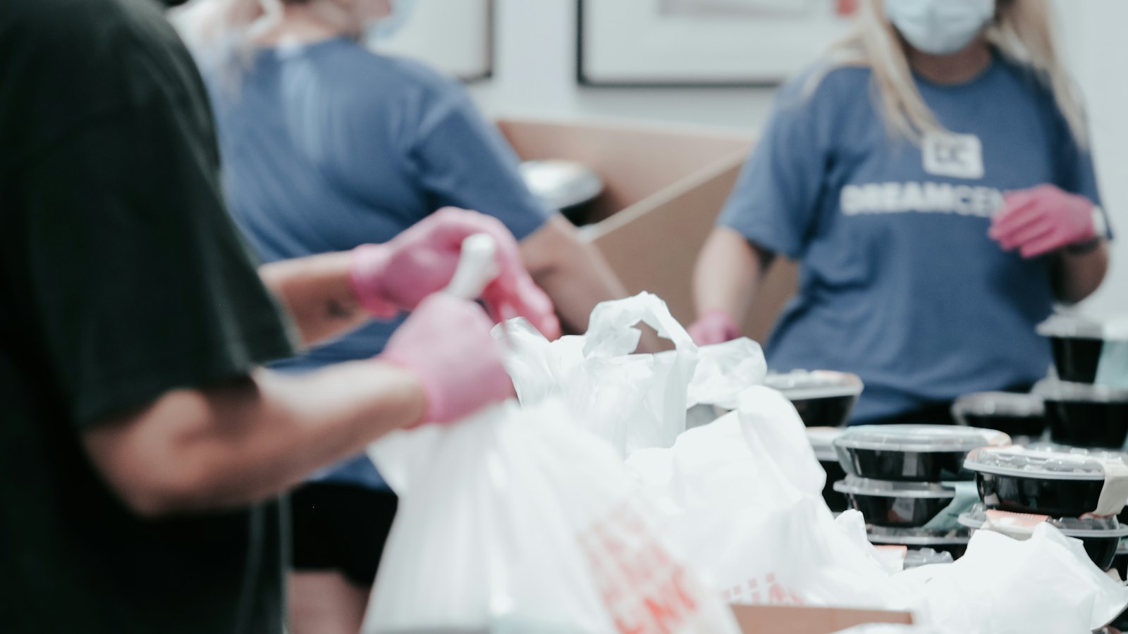 Volunteers in gloves packing food into bags