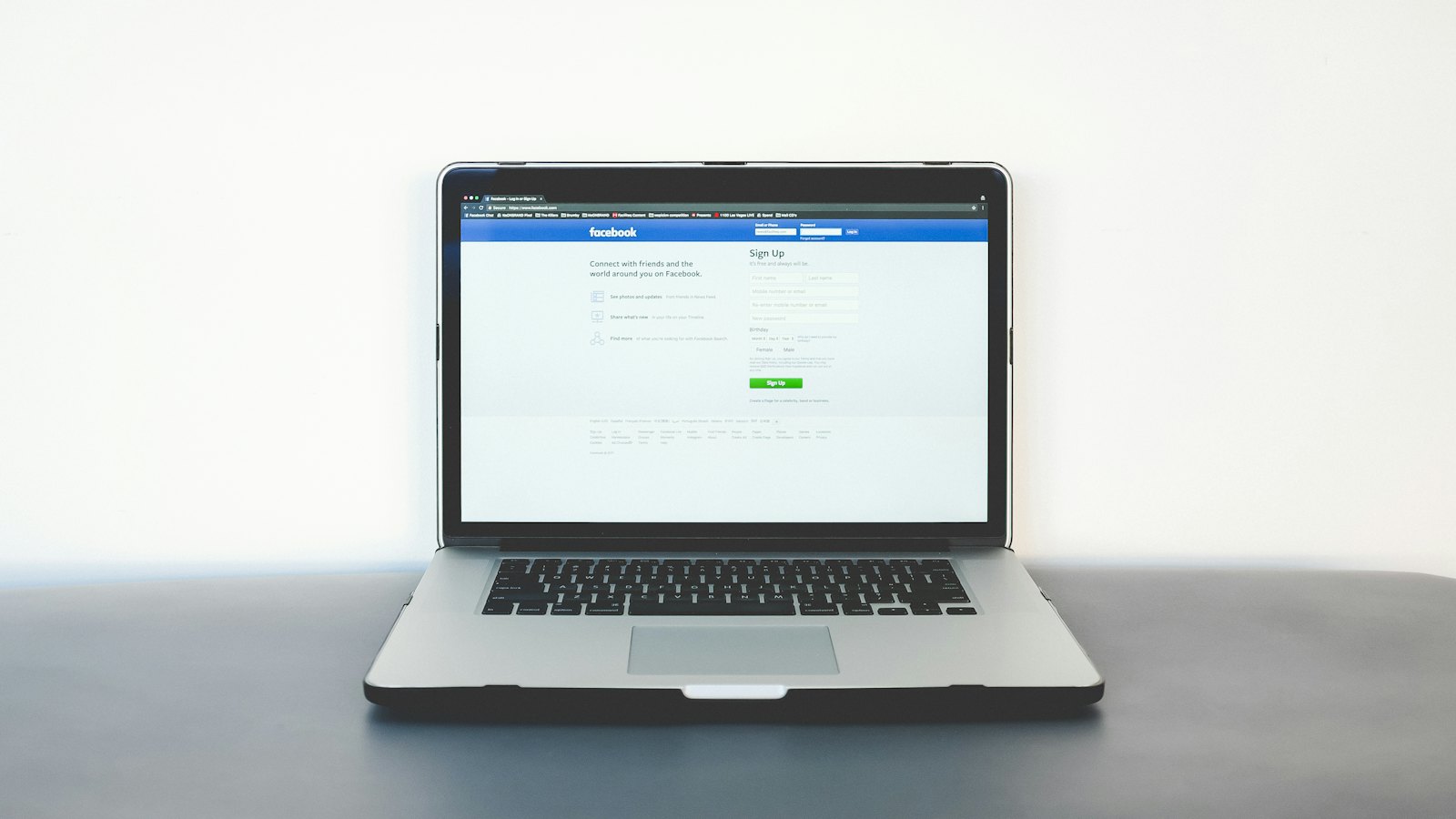 A laptop on a dark table with a social media login page on screen