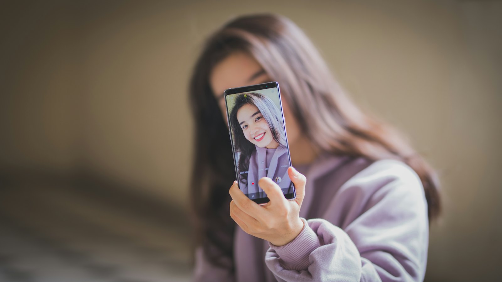 A woman holding up a phone showing her own selfie