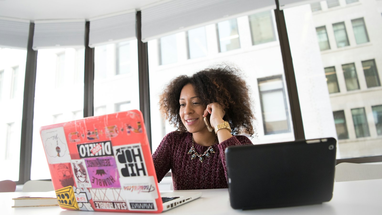 A woman at a desk talking on the phone beside her laptop
