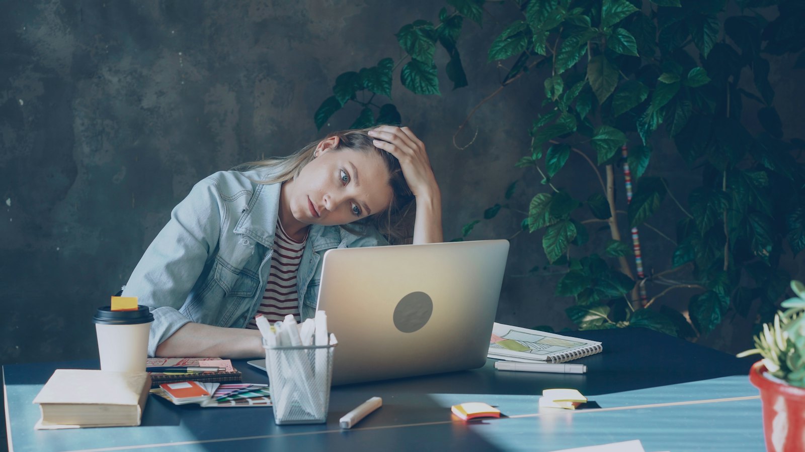 A tired woman leaning on her hand at a laptop