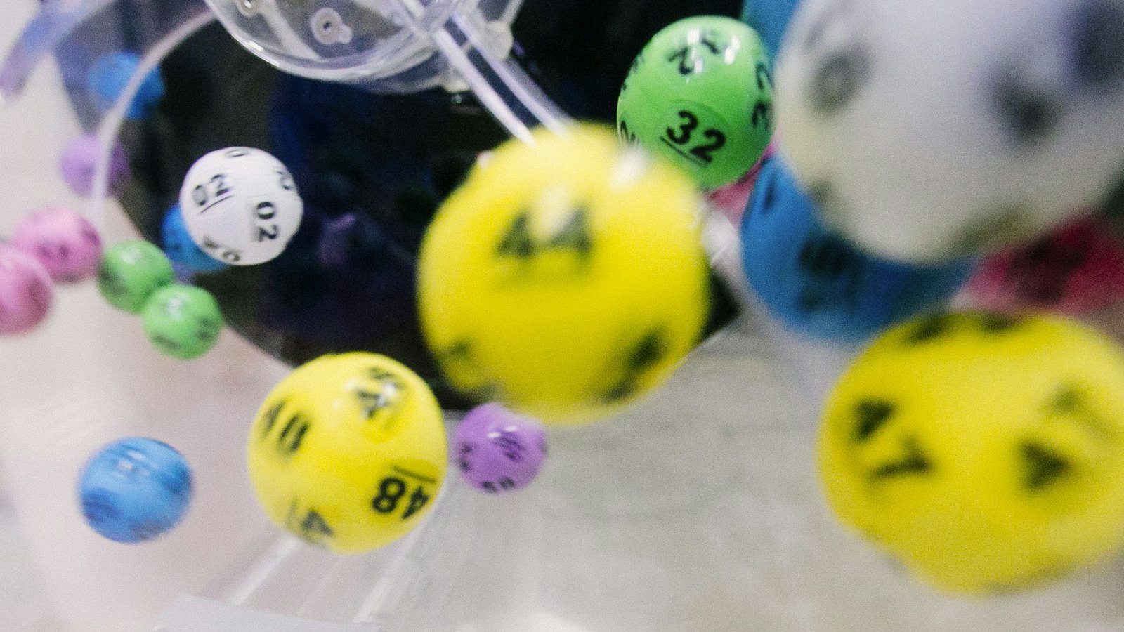 Colourful numbered lottery balls tumbling in a clear drum