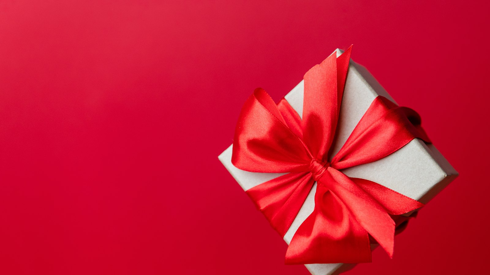 A gift box with a red bow on a red background