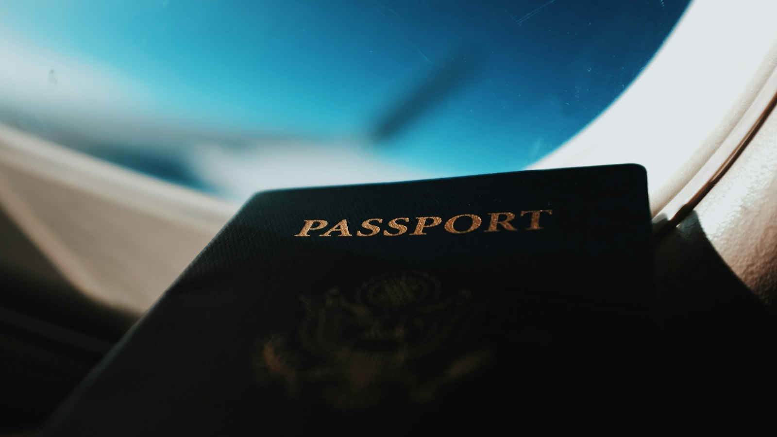 A passport held up in front of an aeroplane window