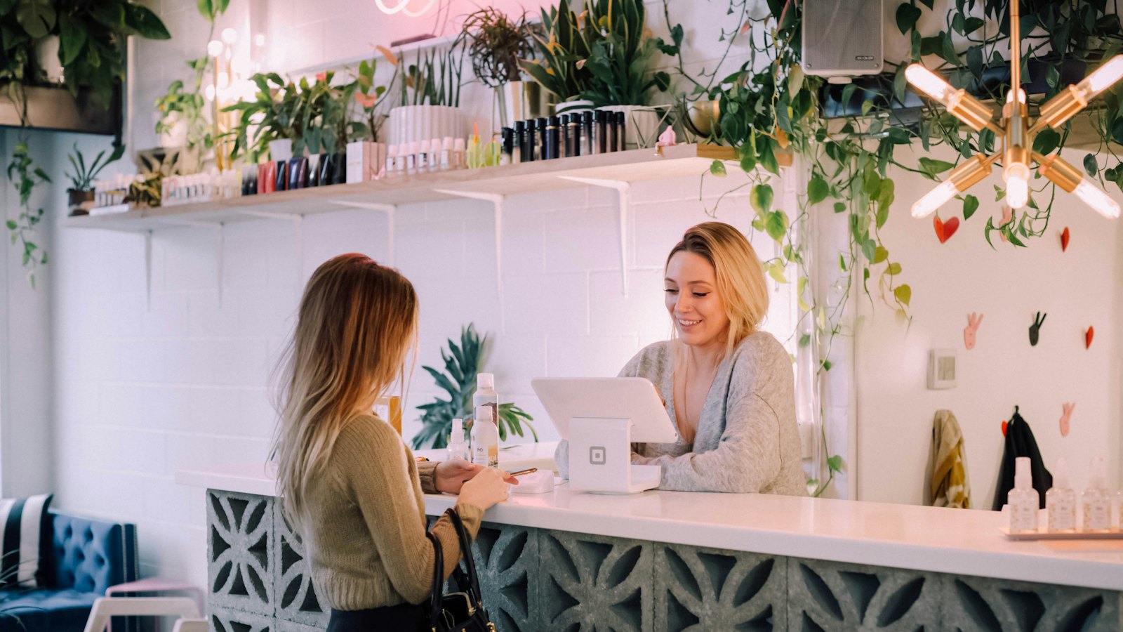 A woman paying at the counter of a plant-filled shop