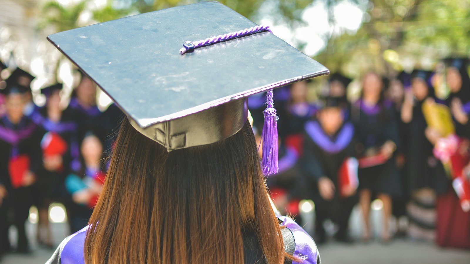 A graduate in a mortarboard seen from behind at a graduation ceremony
