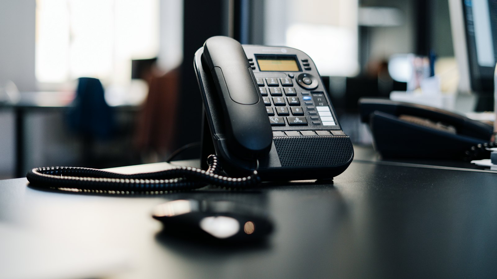 A black office desk phone on a desk