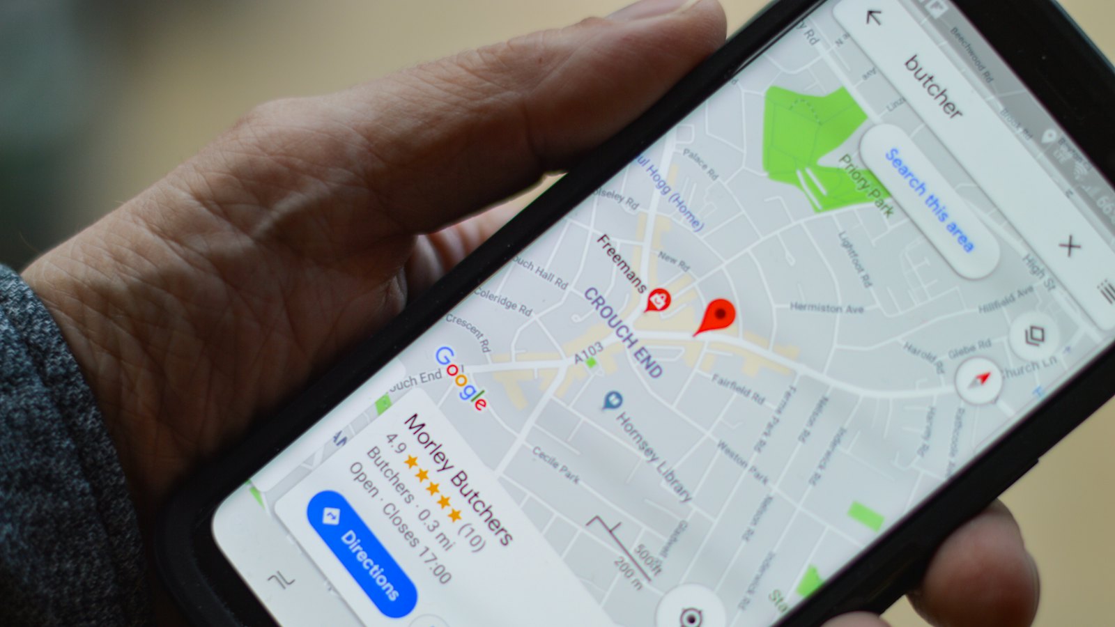 A hand holding a phone showing a map with a location pin