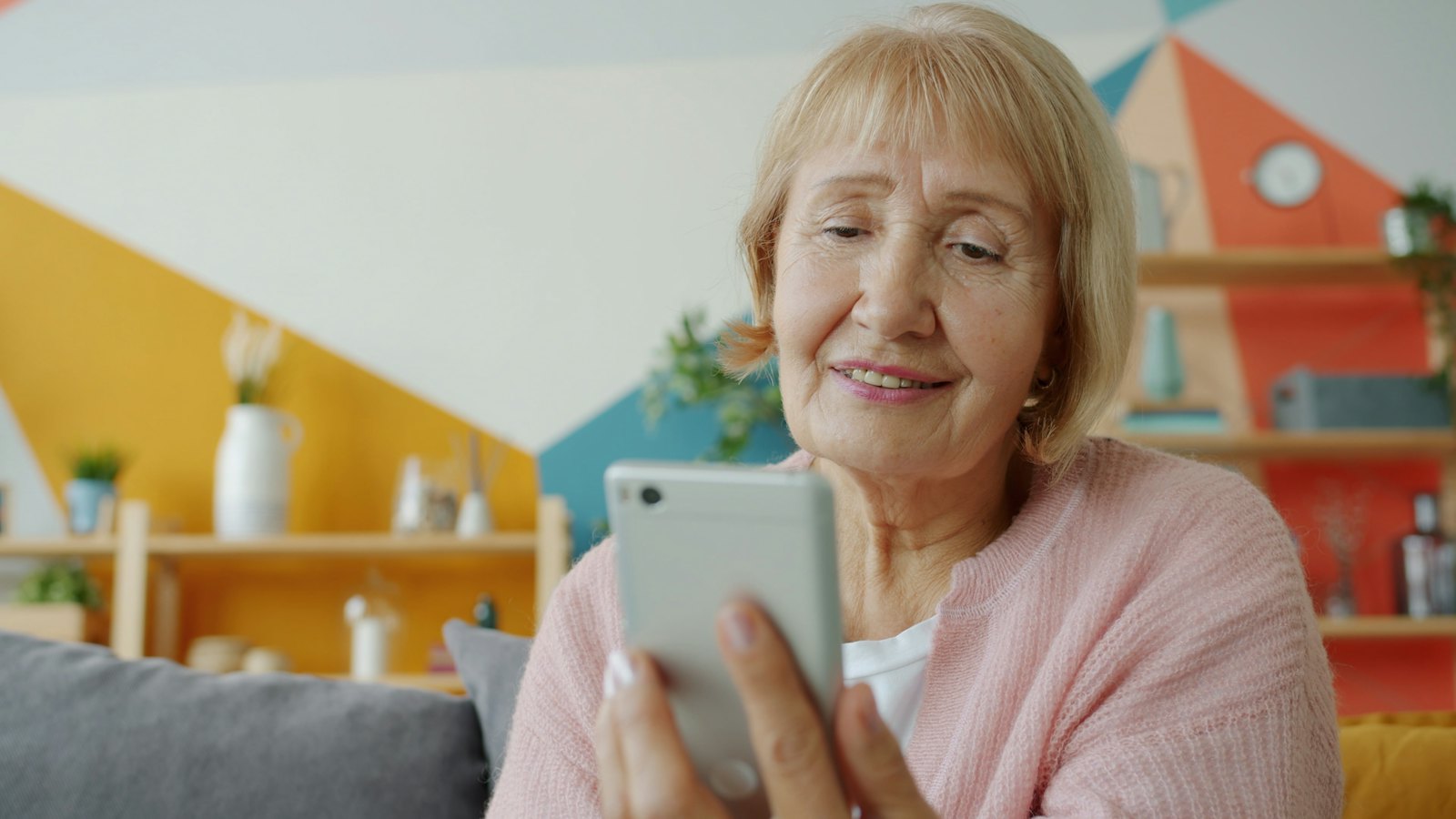 An older woman smiling as she looks at her smartphone
