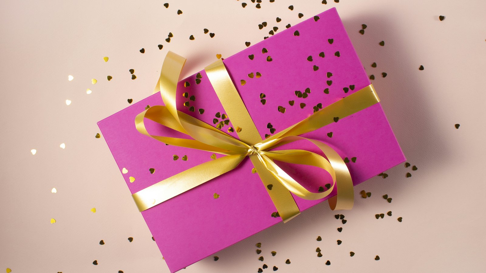 A pink gift box tied with a gold ribbon