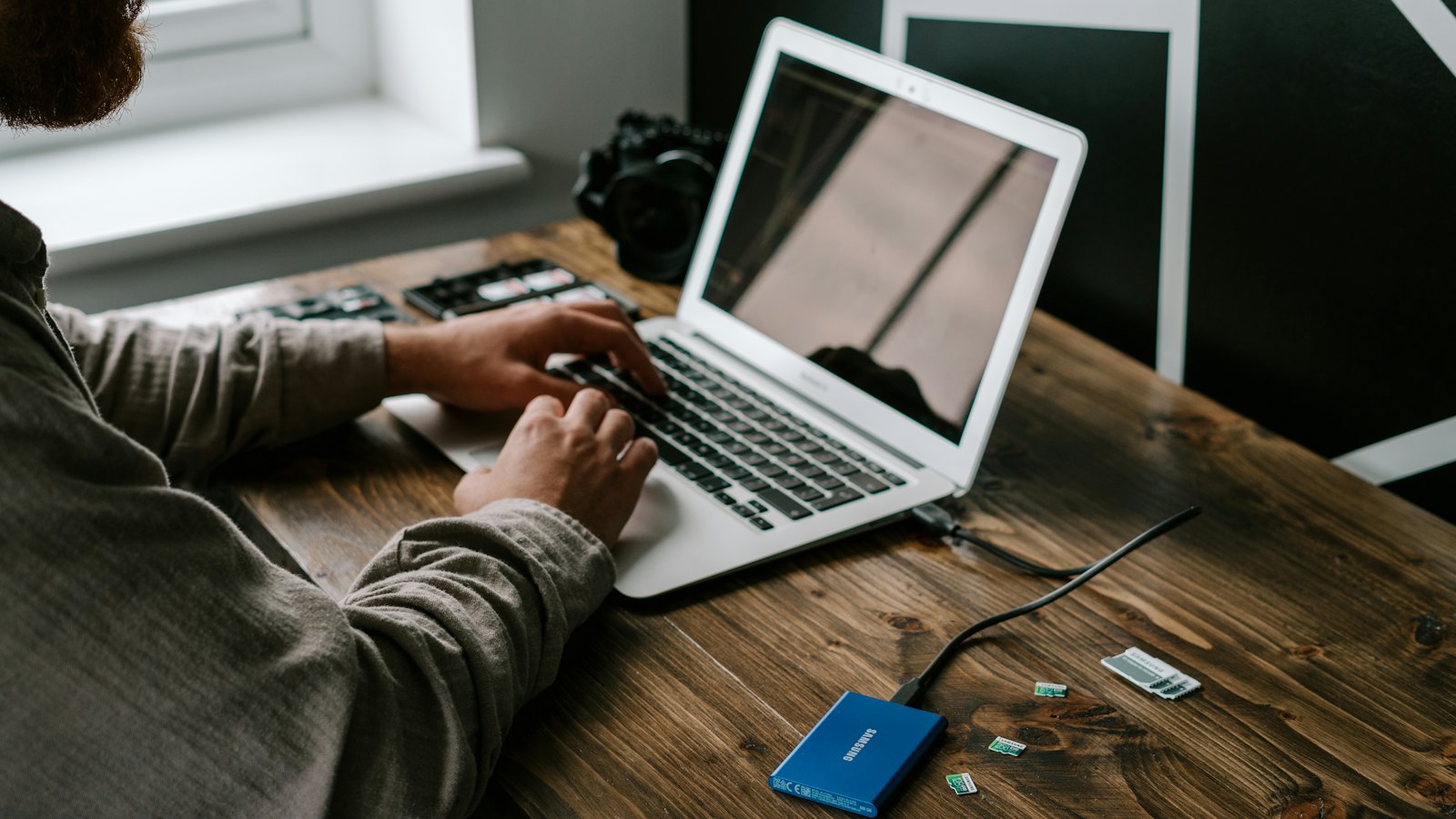 A freelancer working on a laptop at a wooden desk