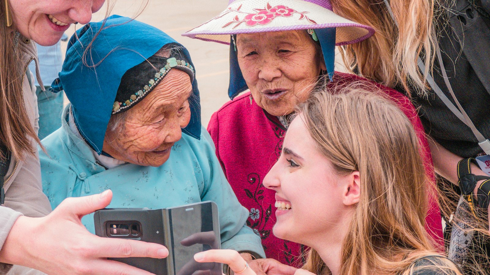 A group of women gathered around a phone, looking at a message