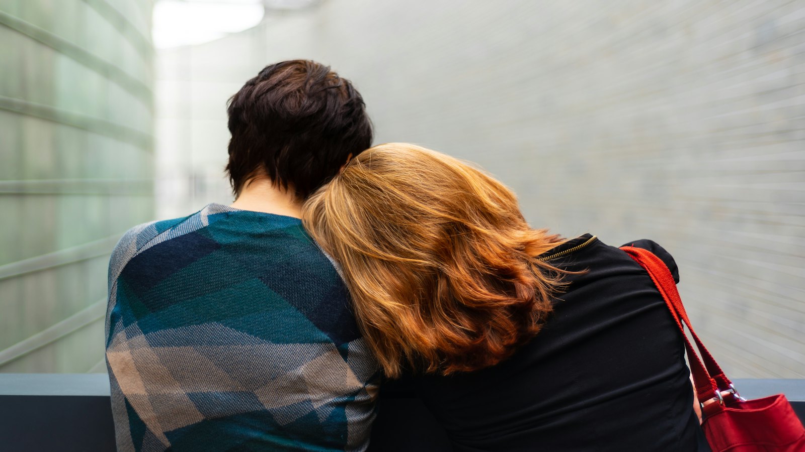 A person resting their head on a friend's shoulder