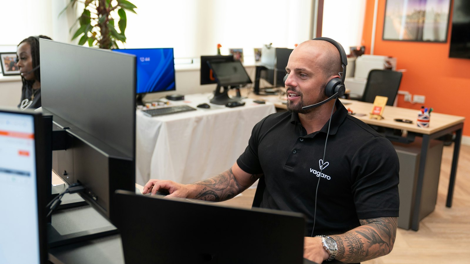 An IT support worker with a headset at his desk