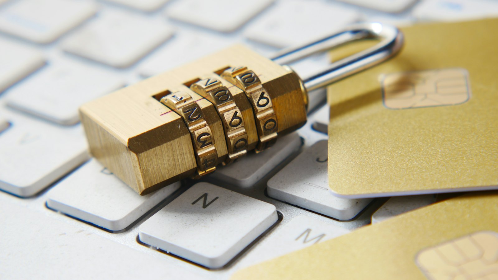 A brass combination padlock resting on a laptop keyboard