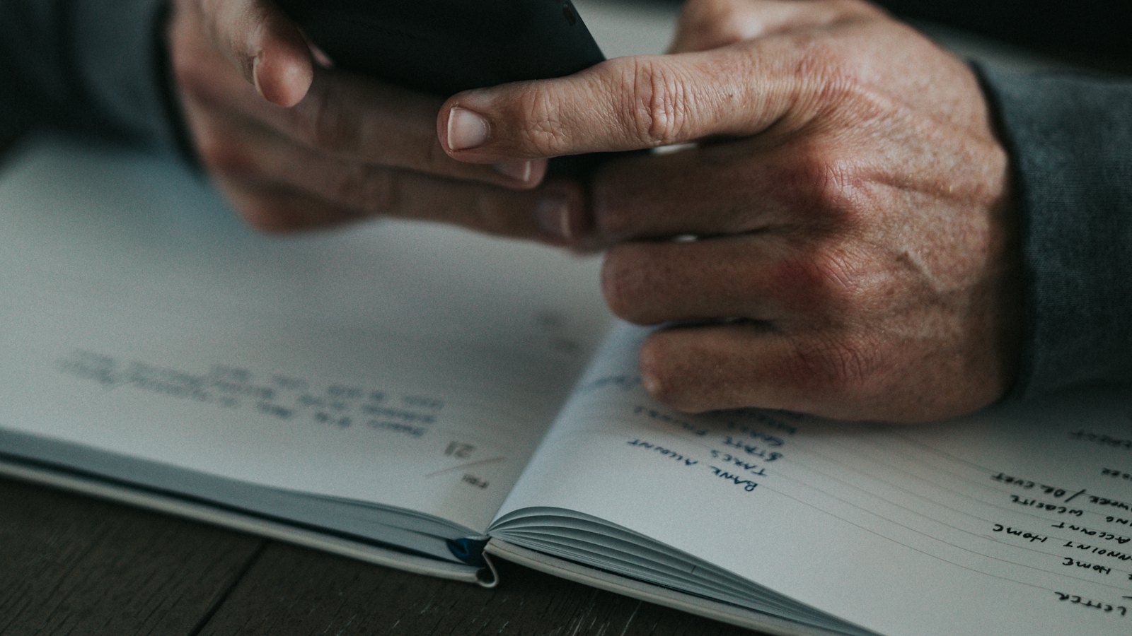 Hands holding a phone above an open notebook with handwritten notes